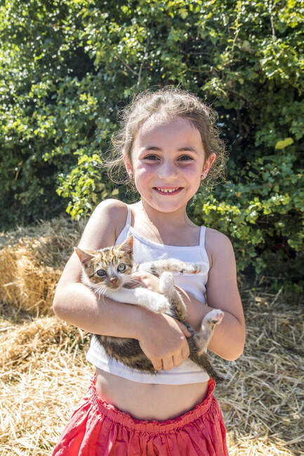 Auvernia - Rhone-Alpes - Haute-Loire - Viaje familiar a la granja. Una niña sosteniendo un gatito en sus brazos. - foto de stock