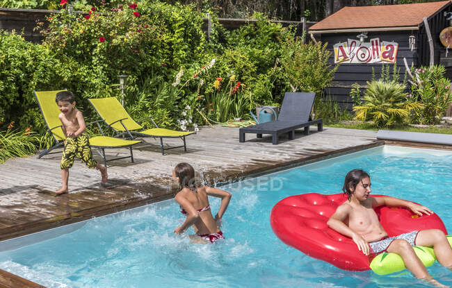 12-year-old girl and two boys of 6 and 14 years old playing in the swimming pool — Stock Photo