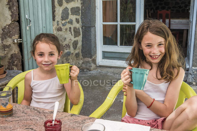 Auvergne - Rhone-Alpes - Haute-Loire - Viagem de família à fazenda. 2 meninas estão felizes bebendo um pouco de leite da fazenda. — Fotografia de Stock