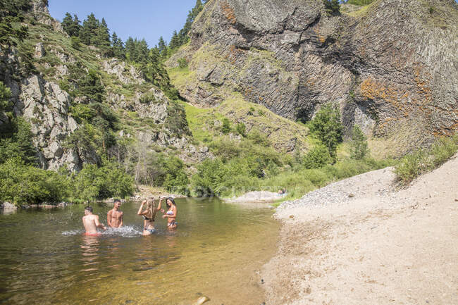 Auvergne, Rhone-Alpes, Haute-Loire at Arlemdes under the basalt cliffs. Four fiends are bathing in the river. — Stock Photo