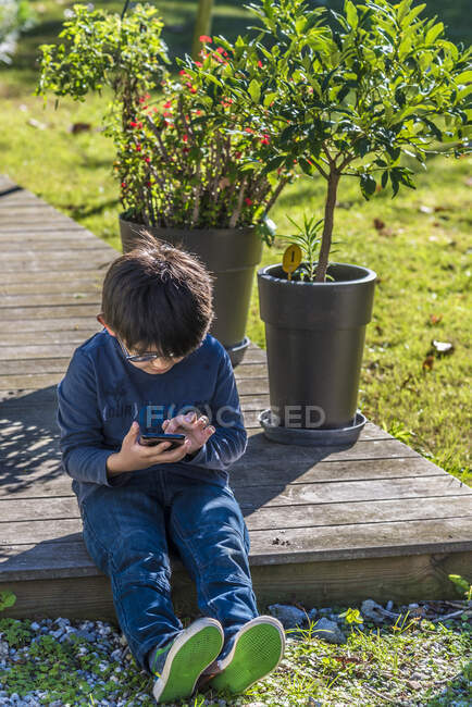 Niño de siete años jugando con un teléfono móvil - foto de stock
