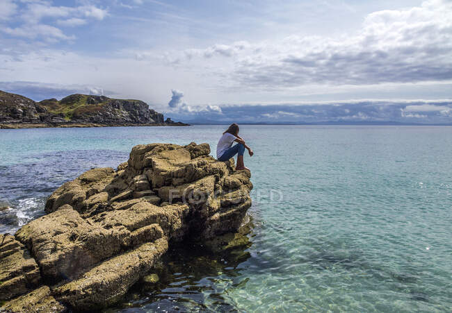 Europa, Gran Bretaña, Escocia, Hébridas, sureste de la Isla de Skye, joven turista en las rocas junto al mar, Punto de Sleat - foto de stock