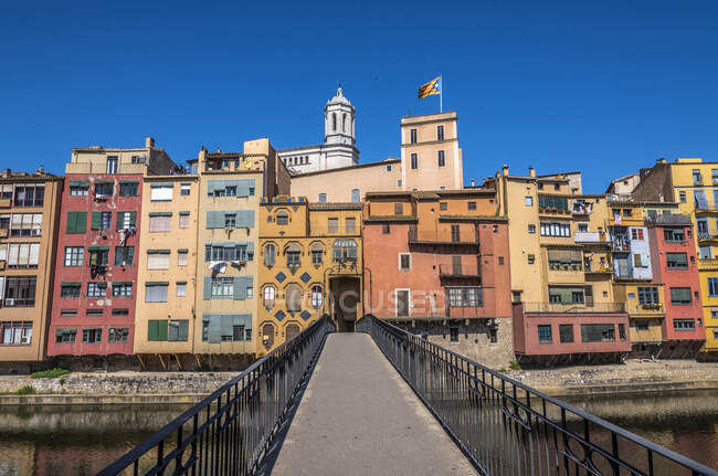 Spanien Katalonien, Girona, Fluss Onyar, Fußgängerbrücke Sant Agusti, farbige Fassaden der Altstadt und Glockenturm der Kathedrale von Girona — Stockfoto