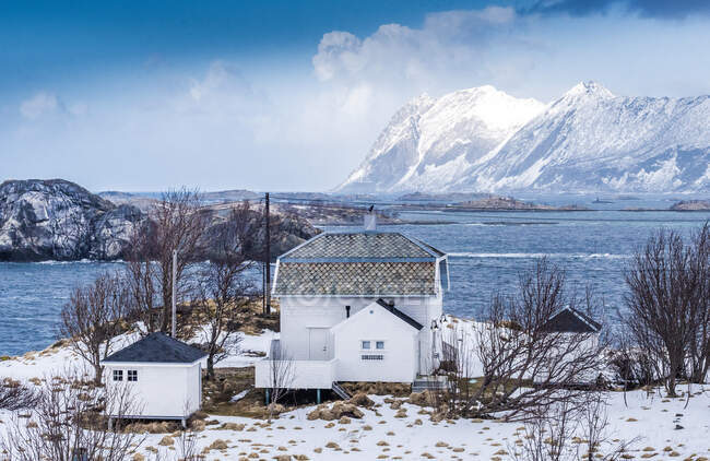 Norvège, Comté de Tromso, Île Senja, maison dans la neige au bord du fjord — Photo de stock