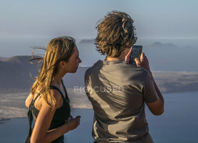 Spain, Canary Islands, Lanzarote Island, Viewpoint from the Mirador del Rio, teenagers photographing the islands of La Graciosa and Montana Clara — Stock Photo