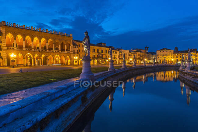 Italia, Véneto, Padua, Prato Della Valle (siglo XVIII), Loggia Amulea (siglo XVII) y estatuas de hombres famosos de Padua a lo largo del canal - foto de stock