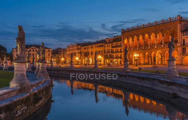 Italia, Véneto, Padua, Prato Della Valle (siglo XVIII), Loggia Amulea (siglo XVII) y estatuas de hombres famosos de Padua a lo largo del canal - foto de stock
