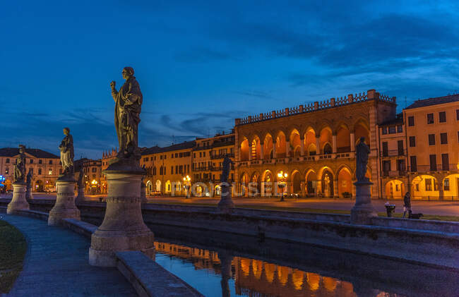 Italia, Véneto, Padua, Prato Della Valle (siglo XVIII), Loggia Amulea (siglo XVII) y estatuas de hombres famosos de Padua a lo largo del canal - foto de stock