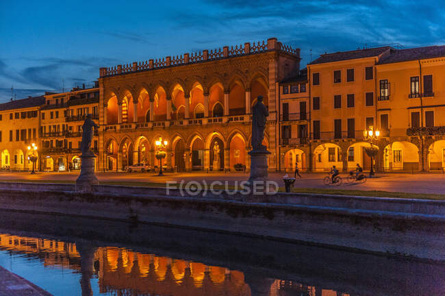 Italia, Véneto, Padua, Prato Della Valle (siglo XVIII), Loggia Amulea (siglo XVII) y estatuas de hombres famosos de Padua a lo largo del canal - foto de stock