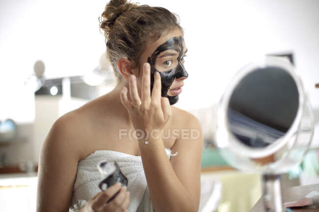 Дівчинка - підліток з масками обличчя у ванній кімнаті. — стокове фото