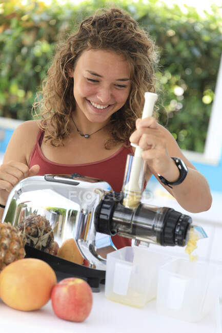 Young woman using a juice extractor — Stock Photo