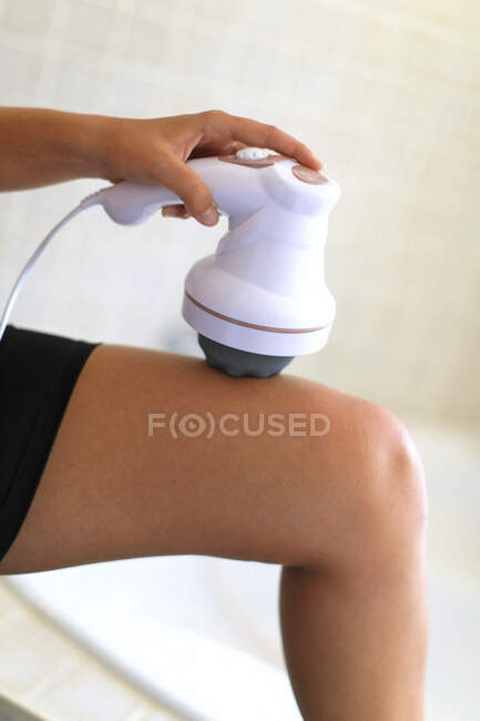 Jeune femme utilisant un masseur anti-cellulite — Photo de stock