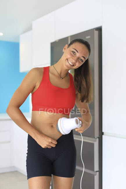 Jeune femme utilisant un masseur anti-cellulite — Photo de stock