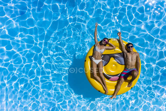 Jeune couple et bouée souriante à la piscine — Photo de stock