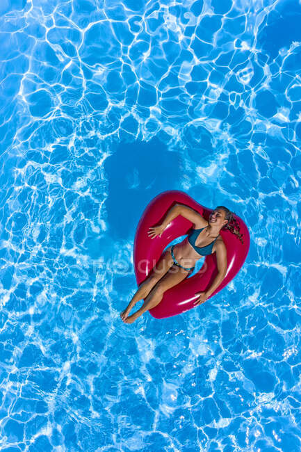 Jovem mulher na piscina com uma bóia em forma de coração vermelho — Fotografia de Stock