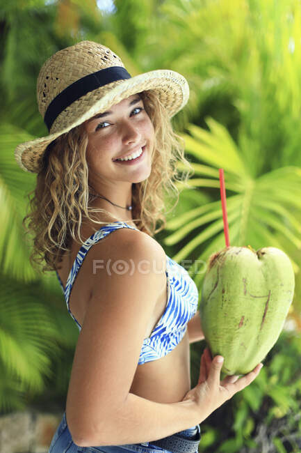 Porträt eines exotischen Mädchens, das aus einer Kokosnuss trinkt — Stockfoto