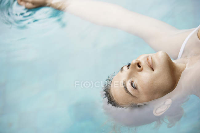 Attraente giovane donna galleggiante su acqua blu . — Foto stock