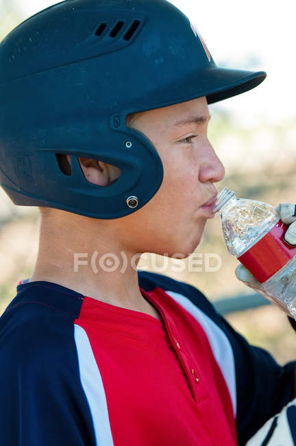 Teenage baseball player drinking water — Stock Photo