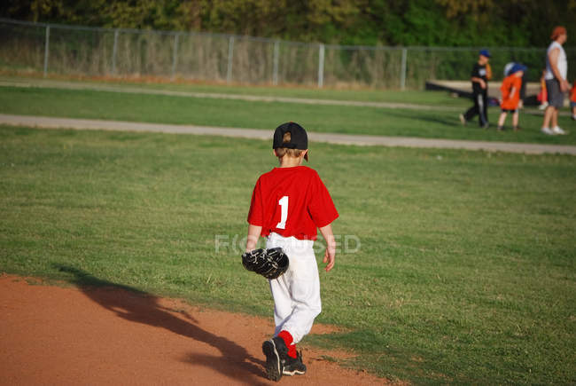 Joven jugador de béisbol caminando en el campo - foto de stock