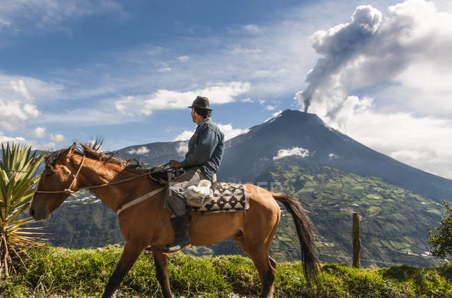 Agricultor em um cavalo olhando para a erupção do vulcão Tungurahua — Fotografia de Stock