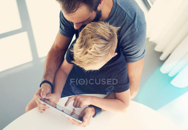 Padre con su hijo usando tableta - foto de stock