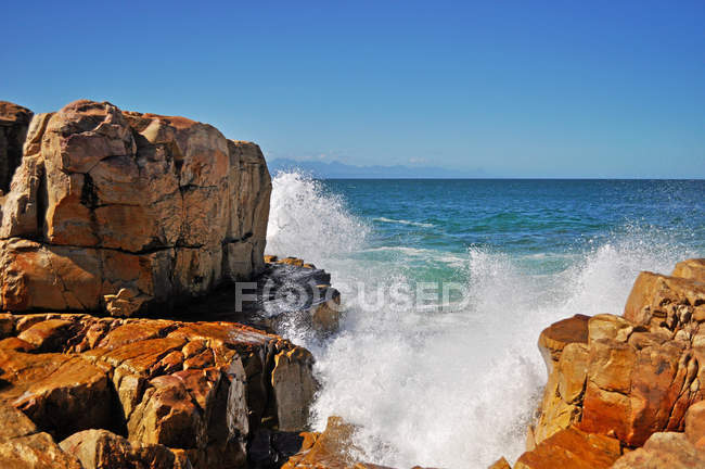 África do Sul: quebrando ondas nas rochas vermelhas da praia da Baía de Plettenberg, chamada Plet ou Plett, originalmente chamada Bahia Formosa, uma cidade ao longo da famosa Rota do Jardim — Fotografia de Stock