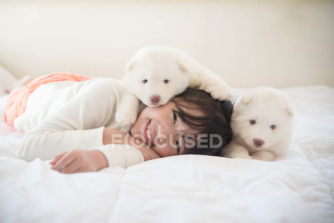 Asiatico ragazza sdraiato con due siberiano husky cuccioli su letto — Foto stock