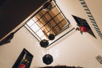Vue du bas des lampes décoratives suspendues au plafond et de beaux pots de fleurs avec des roses sur les fenêtres aux murs au Maroc, Afrique — Photo de stock