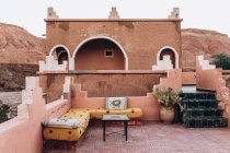 Hermosa vista del antiguo edificio marrón y bancos con almohadas en la terraza en Marruecos, África - foto de stock