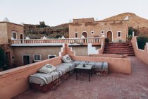 Красивый вид на старое коричневое здание и скамейки с подушками на террасе в Марокко, Африка — стоковое фото
