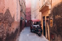 Rua estreita entre casas antigas e transportes locais estacionados fora em Marrocos, África — Fotografia de Stock