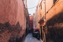 Stretta strada tra vecchie case e trasporti locali parcheggiata fuori in Marocco, Africa — Foto stock