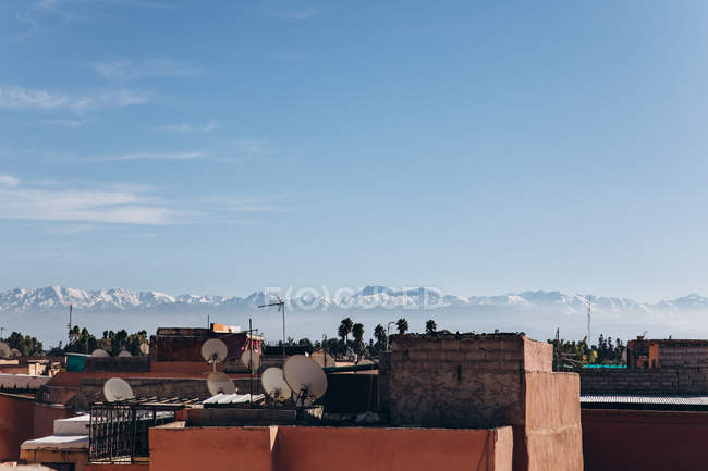 Increíble paisaje urbano de Marrakech con casas tradicionales, tejados y montañas en el día soleado, Marruecos, África - foto de stock