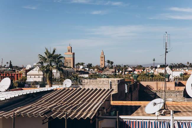 Hermoso paisaje urbano con casas tradicionales, tejados y mezquita con minarete en Marrakech, Marruecos, África - foto de stock