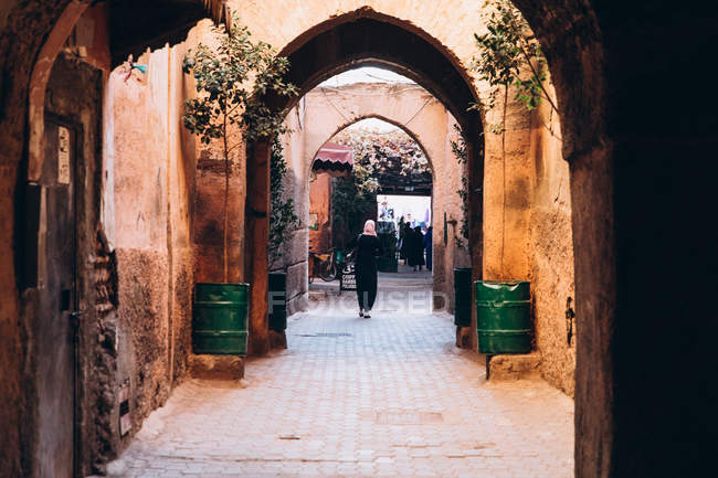 Vue arrière des personnes marchant sur une vieille rue étroite avec des arcades au Maroc, Afrique — Photo de stock