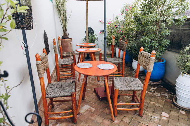 Круглые деревянные столы, уютные стулья и горшечные растения в открытом кафе, Марокко, Африка — стоковое фото