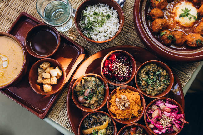 Vista superior de cuencos con comida tradicional marroquí en bandejas en Marruecos, África - foto de stock