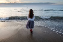 Вид сзади девушки, смотрящей на море, фокус на переднем плане — стоковое фото