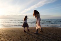 Rückansicht von Mutter mit Tochter am Strand vor wolkenverhangenem Himmel — Stockfoto