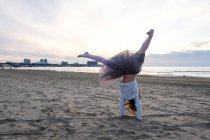 Menina fazendo roda acrobática na praia, foco seletivo — Fotografia de Stock