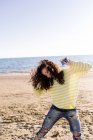 Женщина с кудрявыми волосами слушает музыку на пляже, сосредоточиться на переднем плане — стоковое фото