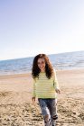 Frau mit lockigem Haar hört Musik am Strand, konzentriert sich auf den Vordergrund — Stockfoto