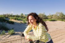 Femme attrayante avec vélo contre la plage, se concentrer sur l'avant-plan — Photo de stock