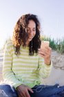 Giovane donna che ascolta musica dallo smartphone in spiaggia, concentrarsi sul primo piano — Foto stock