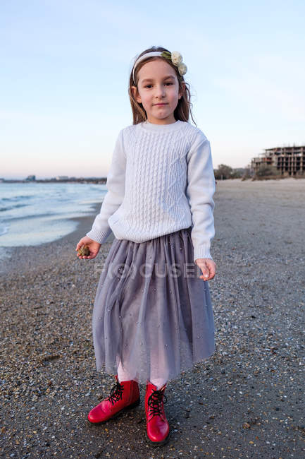 Усміхнена дівчина стоїть на пляжі, зосередитися на передньому плані — стокове фото
