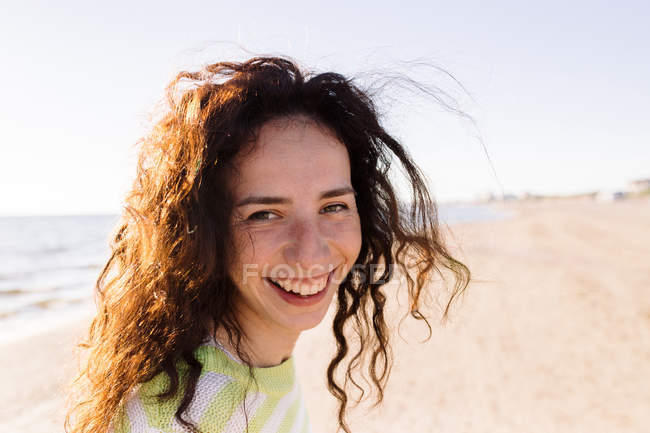 Porträt einer schönen Frau mit lockigem Haar, Meer im Hintergrund — Stockfoto