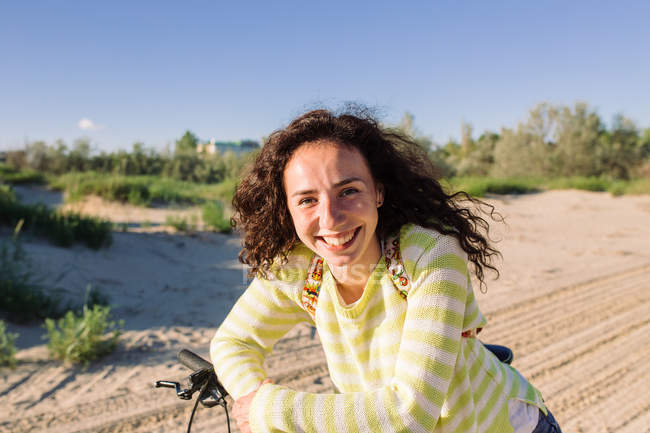 Приваблива жінка з велосипедом на пляжі, зосередитися на передньому плані — стокове фото