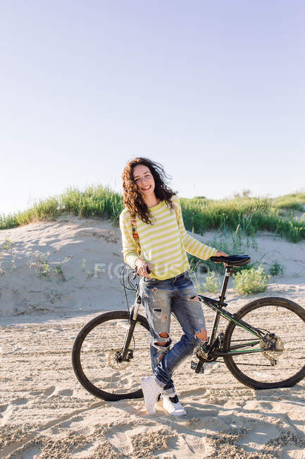 Mulher atraente com bicicleta contra praia, foco em primeiro plano — Fotografia de Stock