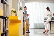 Seitenansicht lächelnder männlicher und weiblicher Mitarbeiter im Gespräch im modernen Büro — Stockfoto