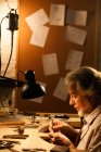 Вид сбоку зрелого ювелира, работающего с инструментами в мастерской — стоковое фото